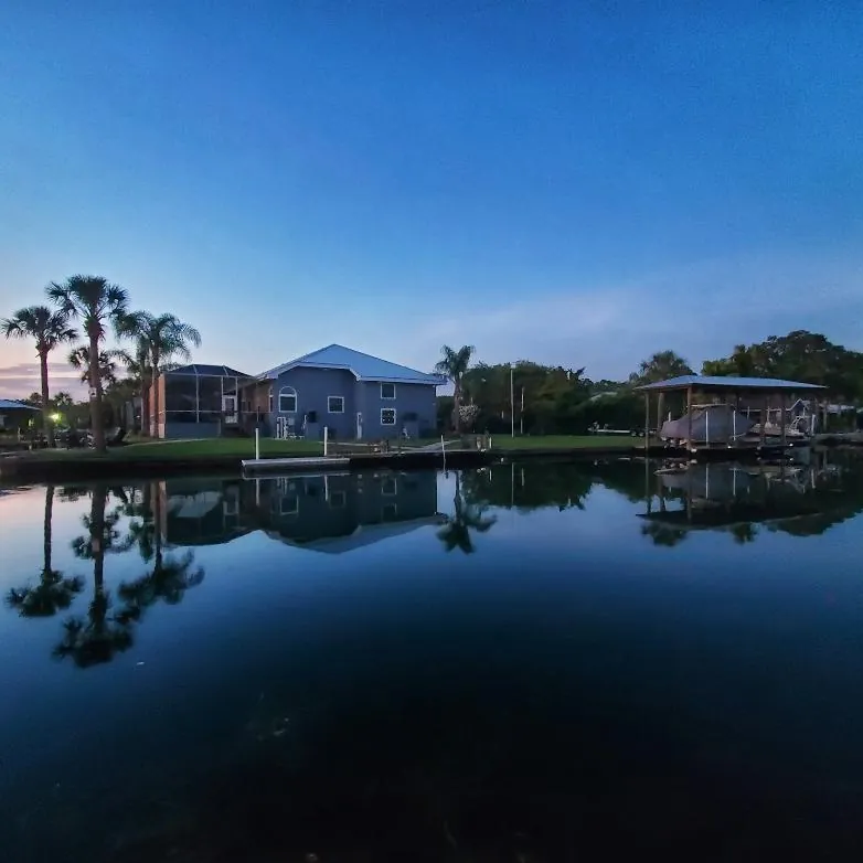 Canal-front homes and palm trees reflected in still water at dusk