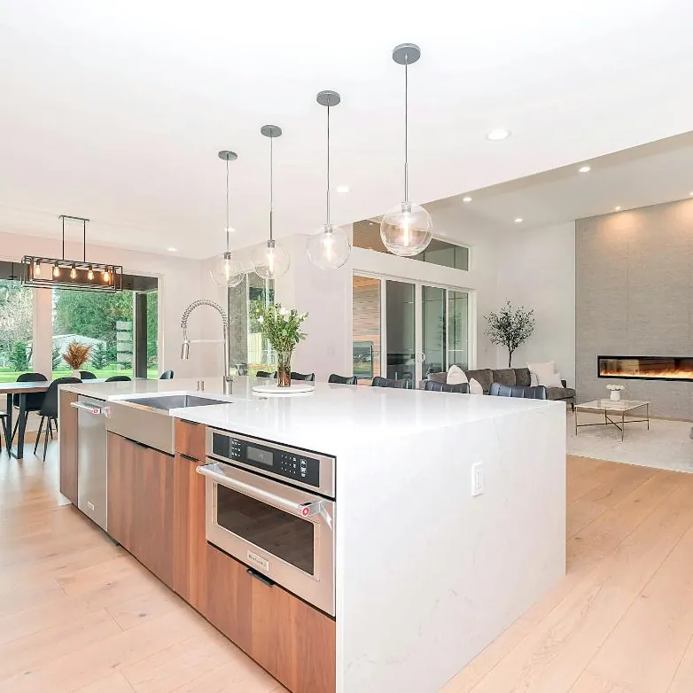 A bright open kitchen with a waterfall island and pendant lights