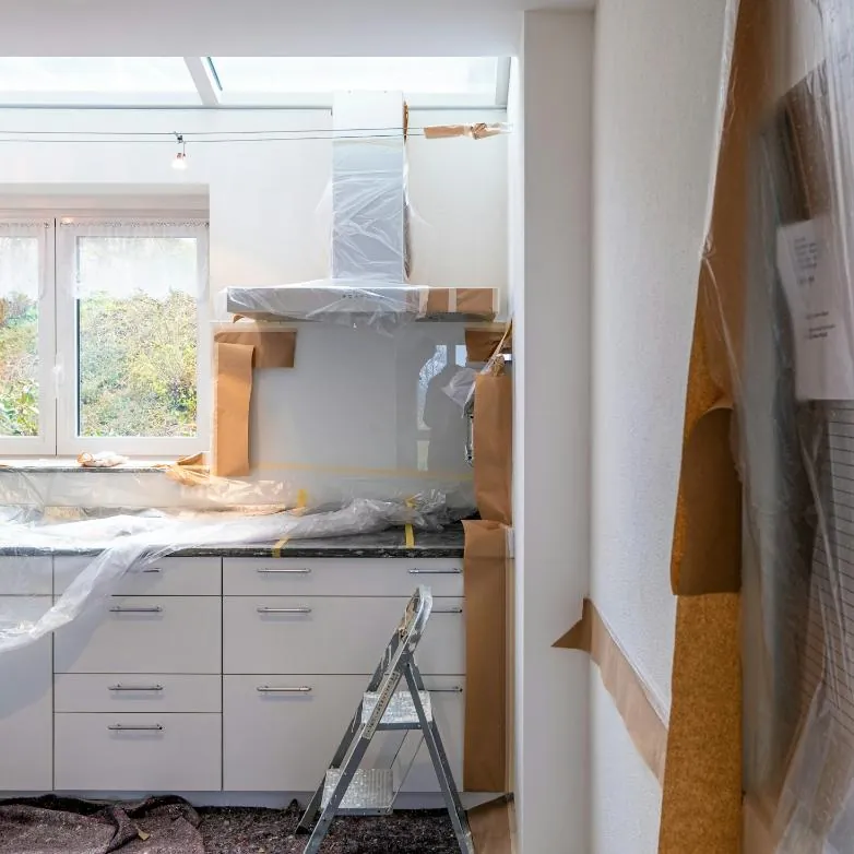 A kitchen under renovation, cabinets and counters wrapped in plastic